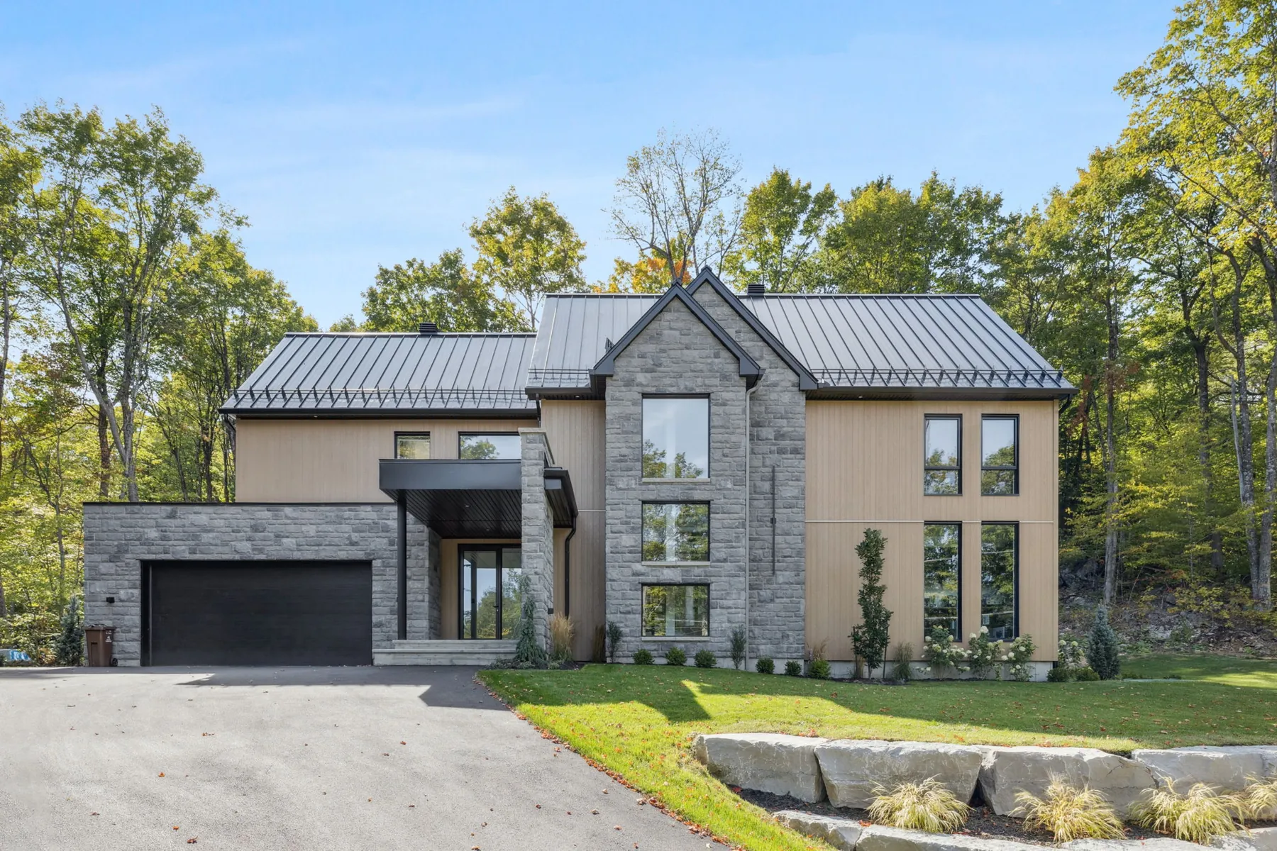 Façade contemporaine avec pierre, bois et toiture métallique